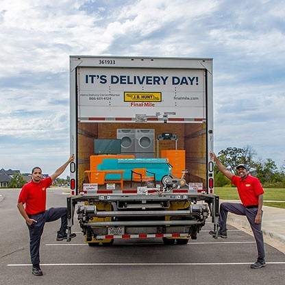 J.B. Hunt delivery truck with two smiling delivery workers in red shirts ready for delivery