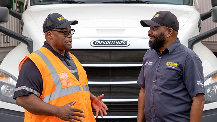Two J.B. Hunt drivers standing in front of a parked truck conversing.