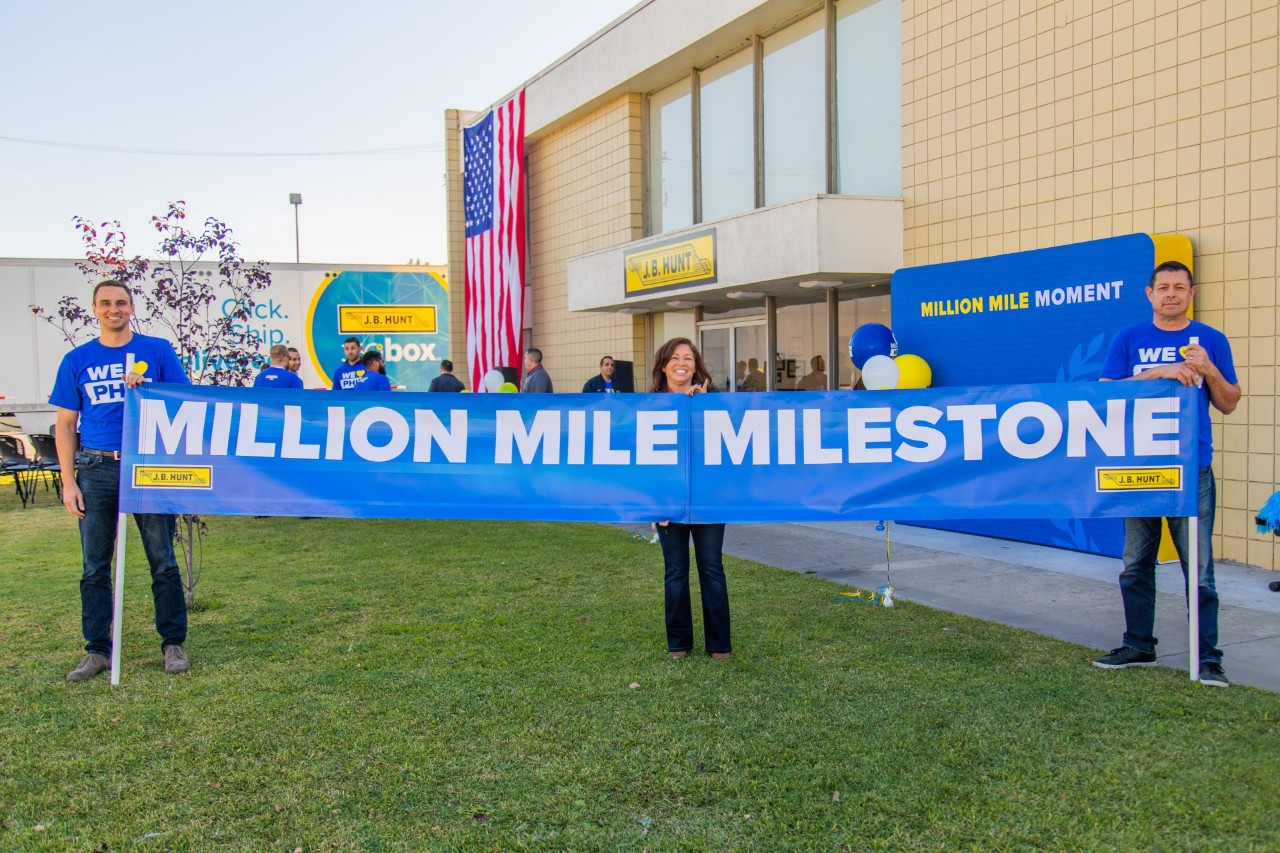 J.B. Hunt employees holding a sign that reads, "Million Mile Milestone" at the Million Mile event.