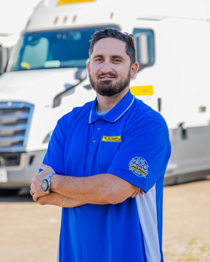 J.B. Hunt driver Chad stands and smiles at a camera.