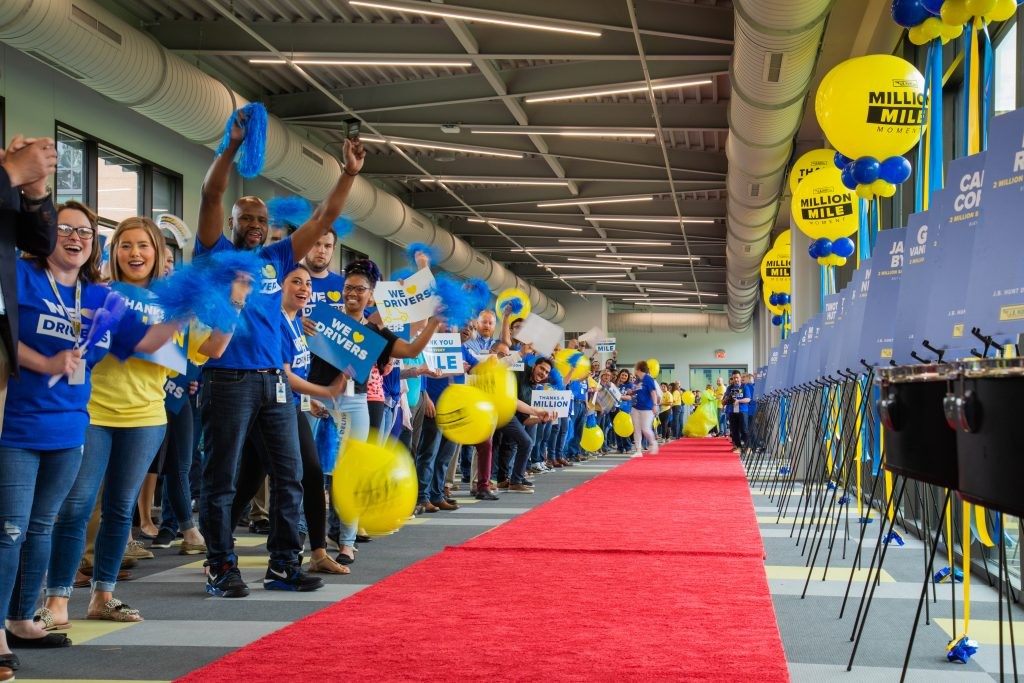 J.B. Hunt employees lined up along red carpet holding signs and pom-poms, cheering for million mile drivers during the annual Million Mile Walk of Fame.