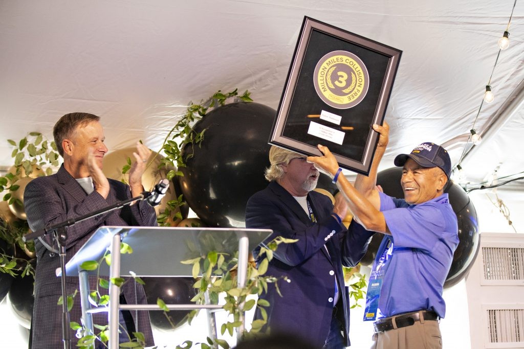 3 million mile driver celebrating on stage with his award.