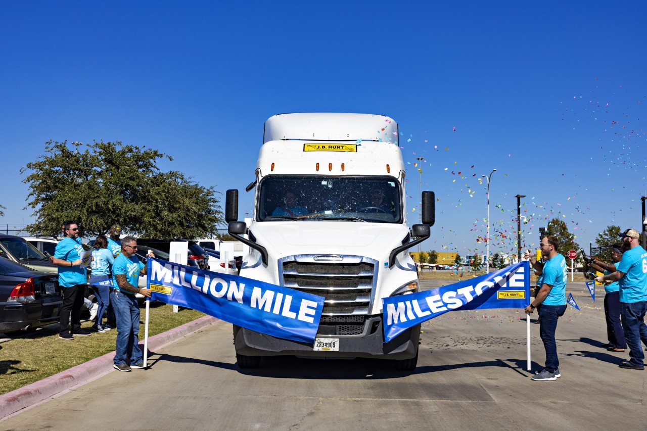 Tony driving through a banner with the words "Million Mile Milestone" as a group of people celebrate with confetti around the truck.