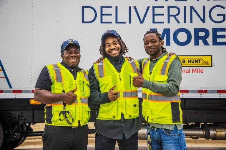Three J.B. Hunt FMS drivers stand together and smile, giving thumbs up.