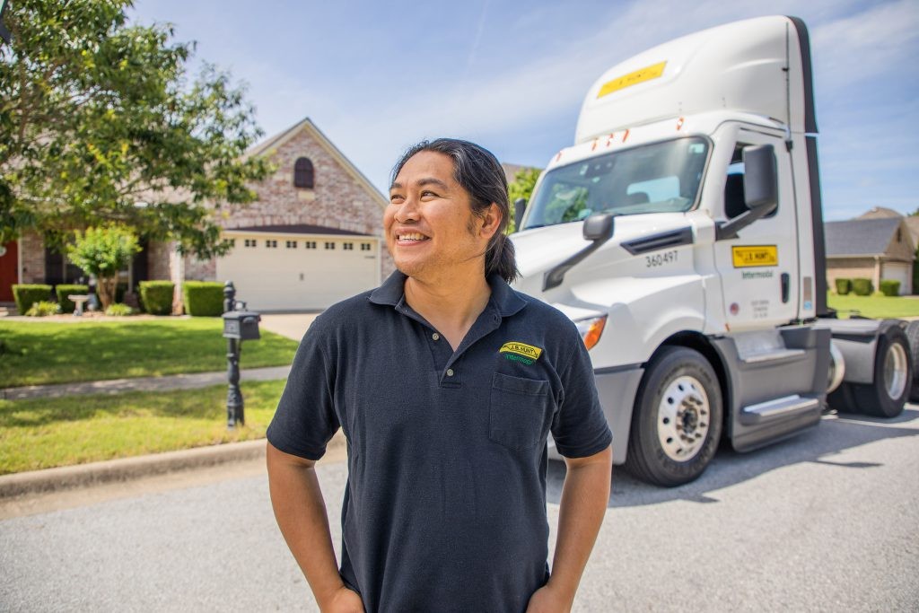 J.B. Hunt driver stands in front of his house and smiles.