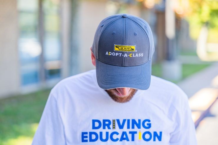 man showing off an adopt-a-class hat