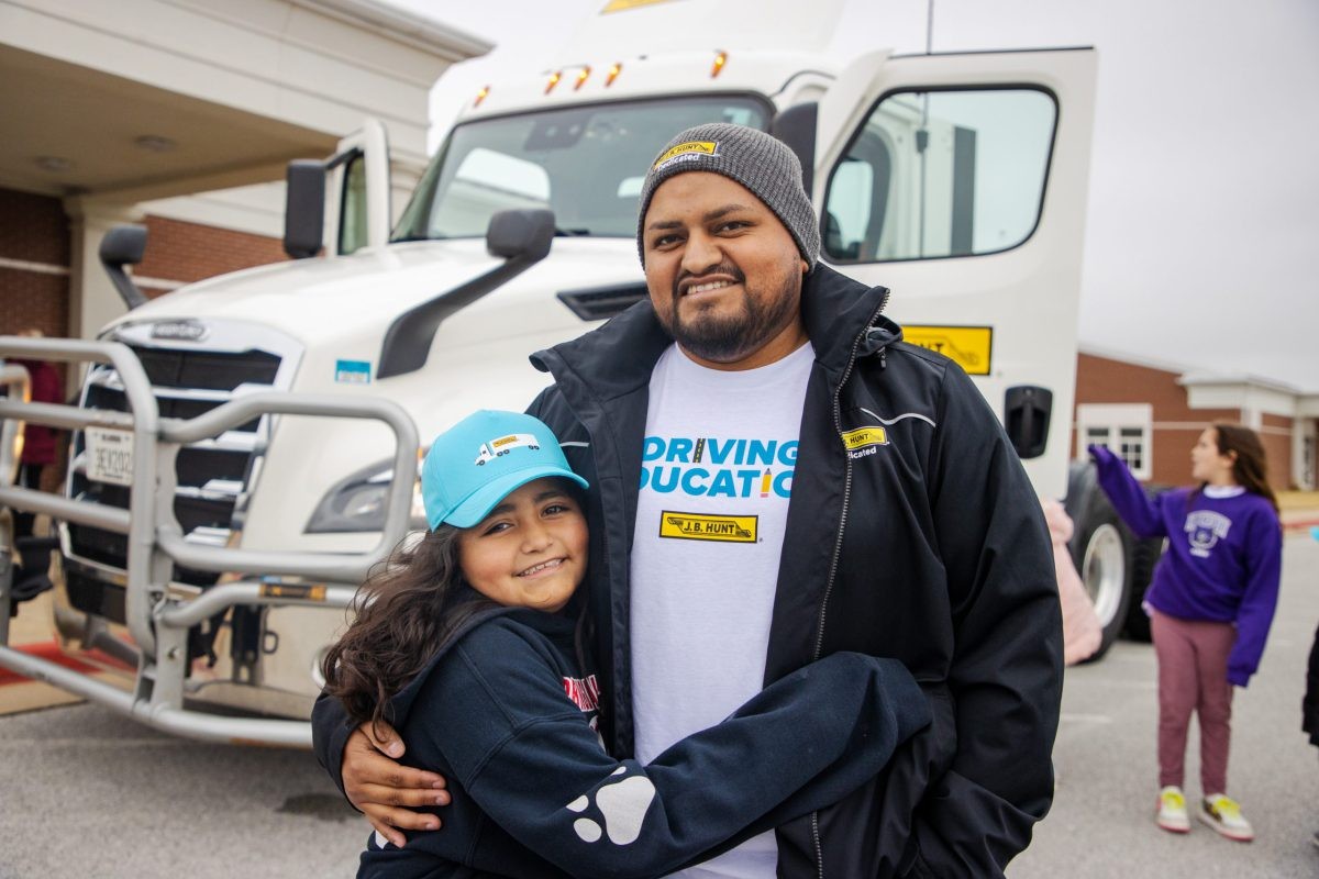 J.B. Hunt driver hugs his daughter after donating supplies to her classroom.