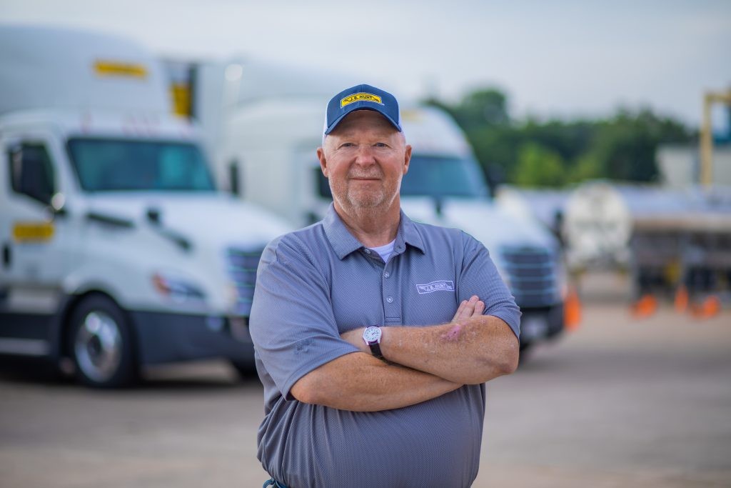 J.B. Hunt driver Wesley stands in front of J.B. Hunt trucks.
