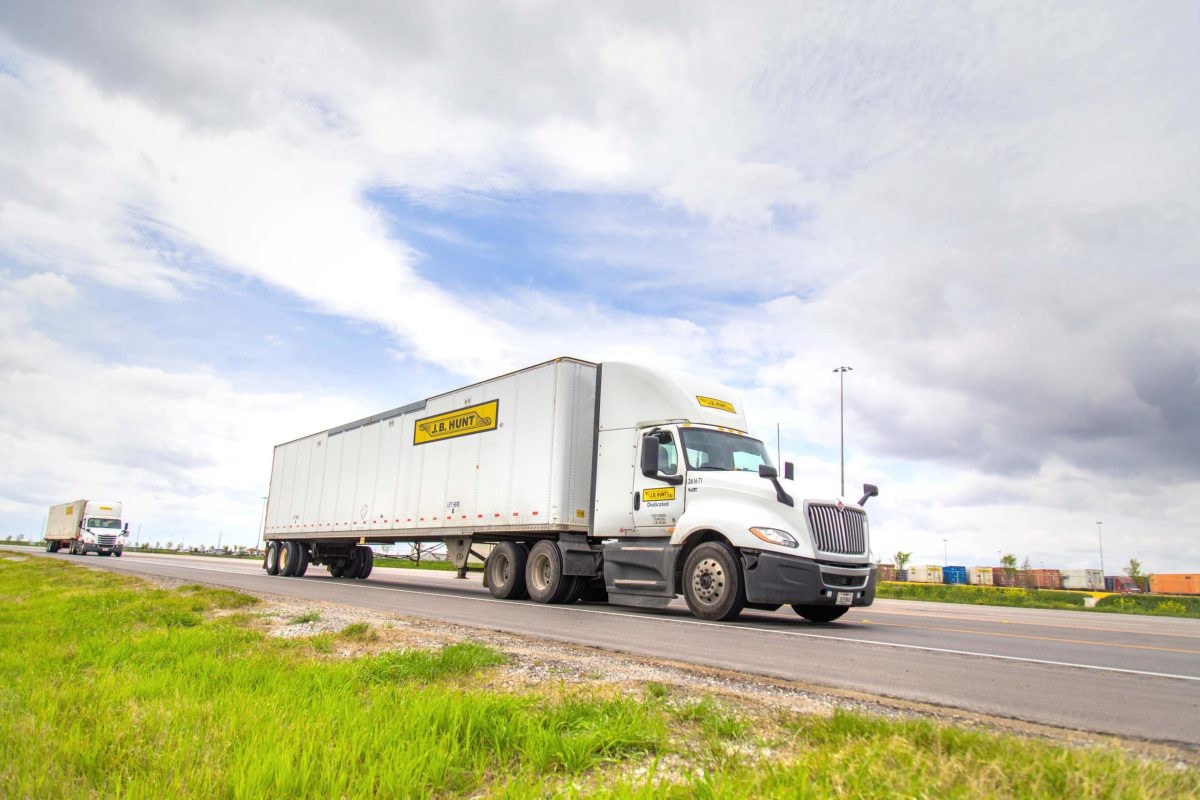 J.B. Hunt DCS day cab and trailer drive down a road.