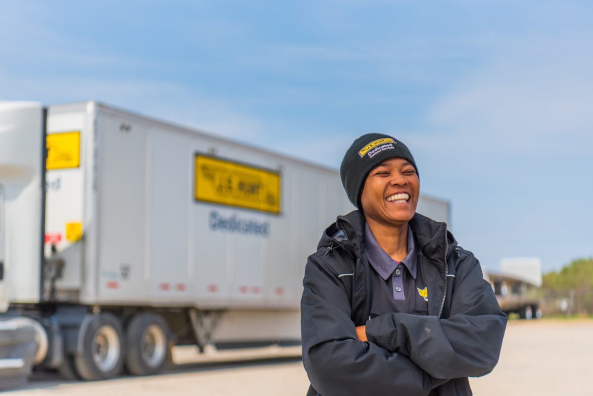 J.B. Hunt Driver, Cheryl, standing in front of J.B. Hunt Dedicated Contract Services truck and laughing.