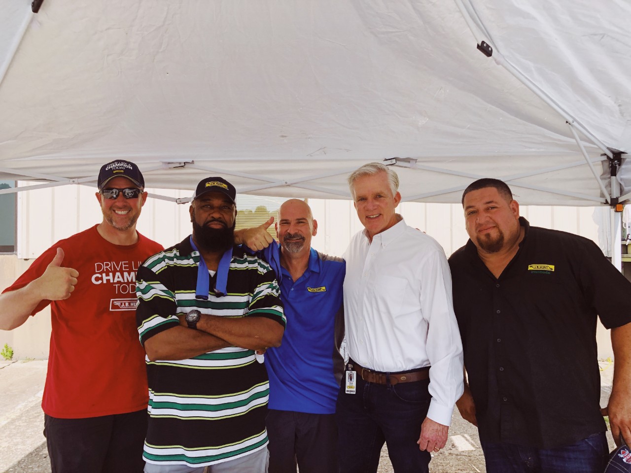 J.B. Hunt employees standing under a canopy smiling for a group photo.