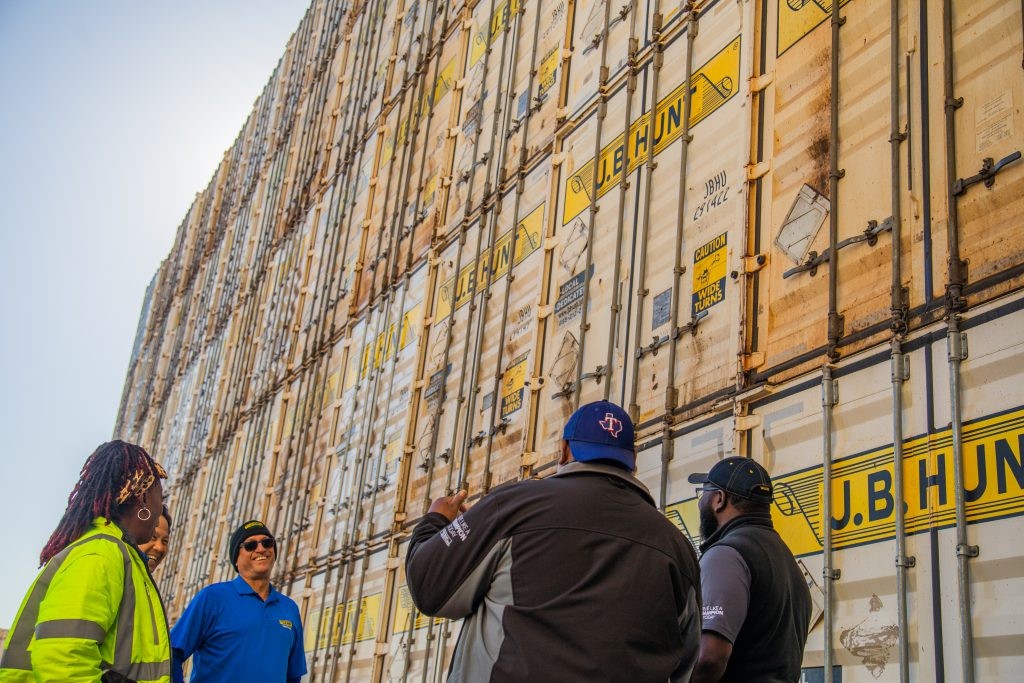Five intermodal drivers stand on front of a stack of J.B. Hunt containers.
