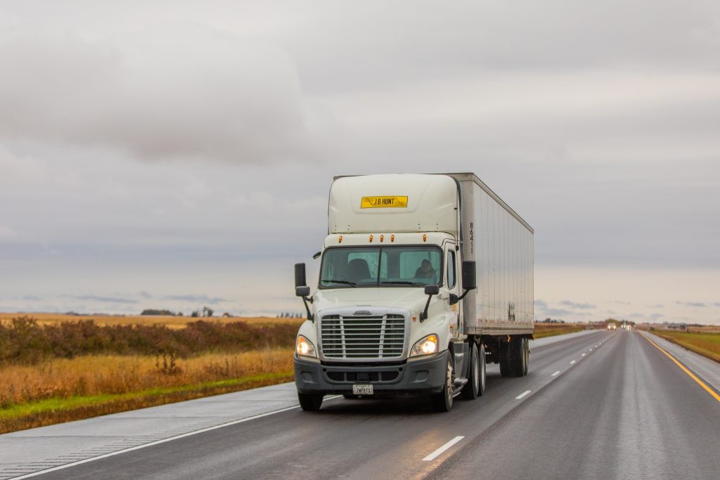 J.B. Hunt day cab and trailer driving on the road.