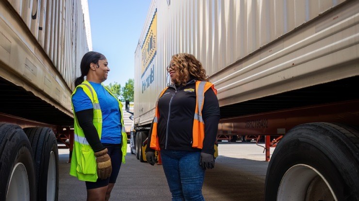 Intermodal driver working with fellow J.B. Hunt employee beside a company truck. 
