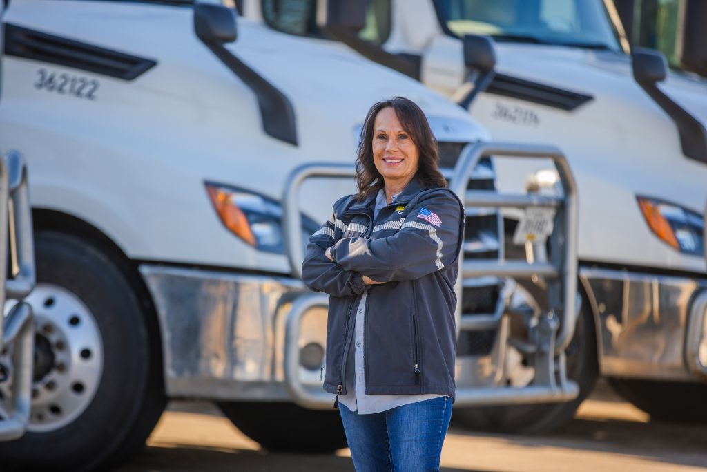 J.B. Hunt Apprenticeship Program graduate stands in front of J.B. Hunt cabs.
