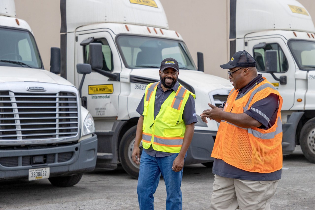 Two J.B. Hunt drivers walking and talking in from of Intermodal trucks.