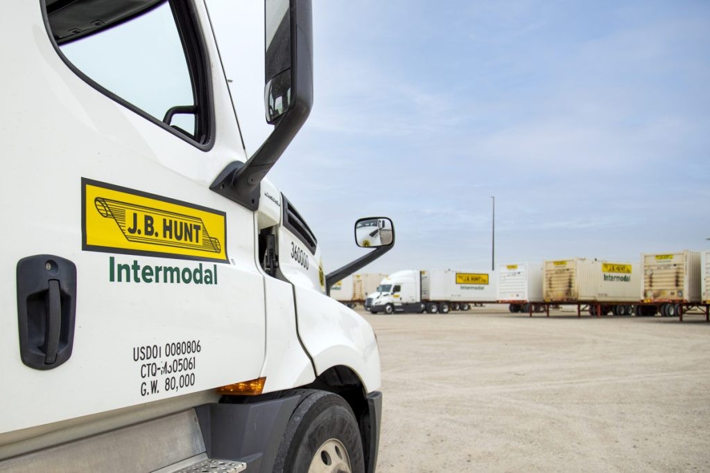 The side of a J.B. Hunt Intermodal truck facing several J.B. Hunt Intermodal truck and trailers in a drop yard.