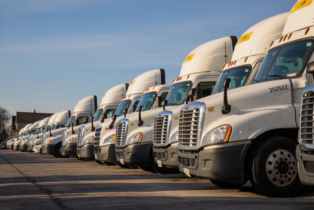 A line of J.B. Hunt trucks lined up in a parking lot.