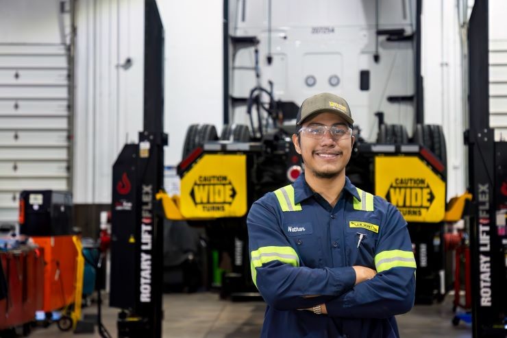 A J.B. Hunt trailer technician stands in a J.B. Hunt shop and smiles.