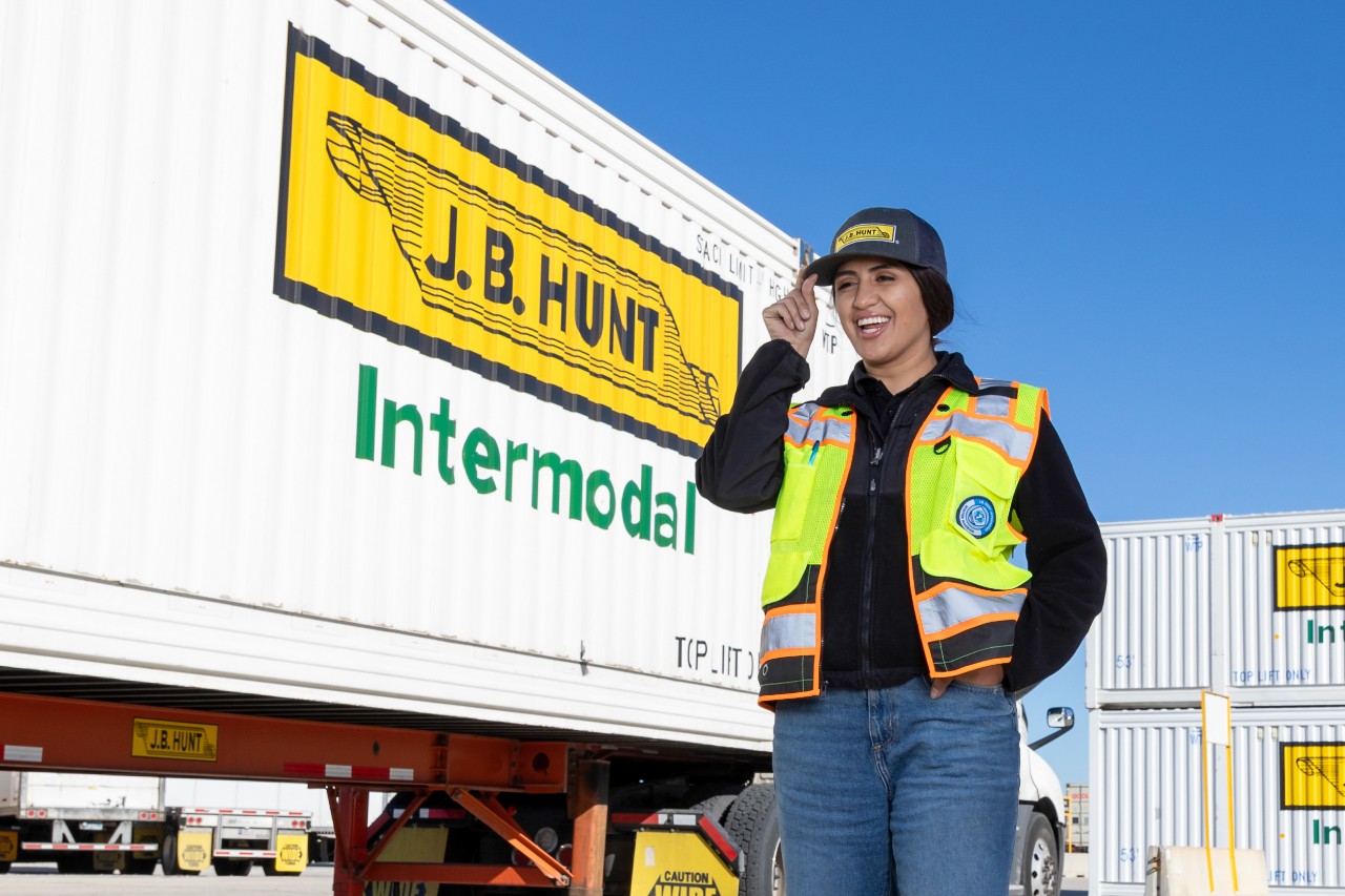 J.B. Hunt Driver, Anais, smiling as she walks next to a J.B. Hunt Intermodal truck