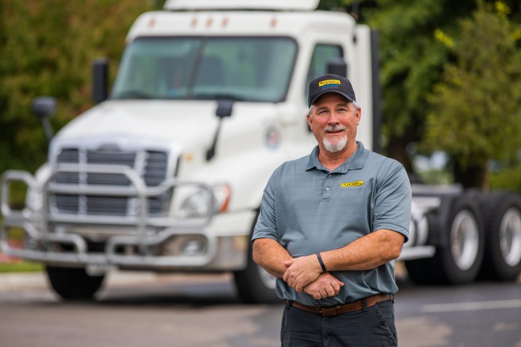 Veteran J.B. Hunt Driver, Paul, standing in front of J.B. Hunt truck.