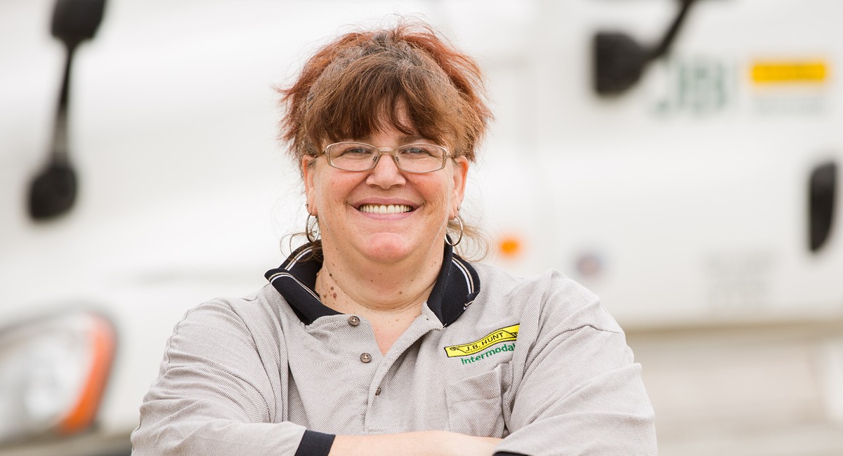Intermodal driver Jodi stands and smiles in front of an intermodal day cab.