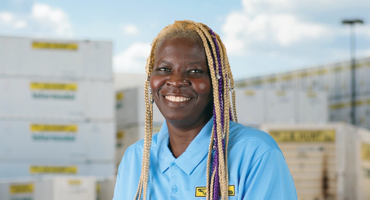 Local driver Monica stands and smiles in front of J.B. Hunt intermodal containers.