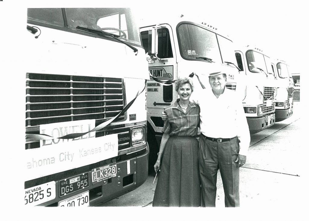 J.B. Hunt founders J.B. and Johnelle Hunt standing in front of J.B. Hunt semi trucks