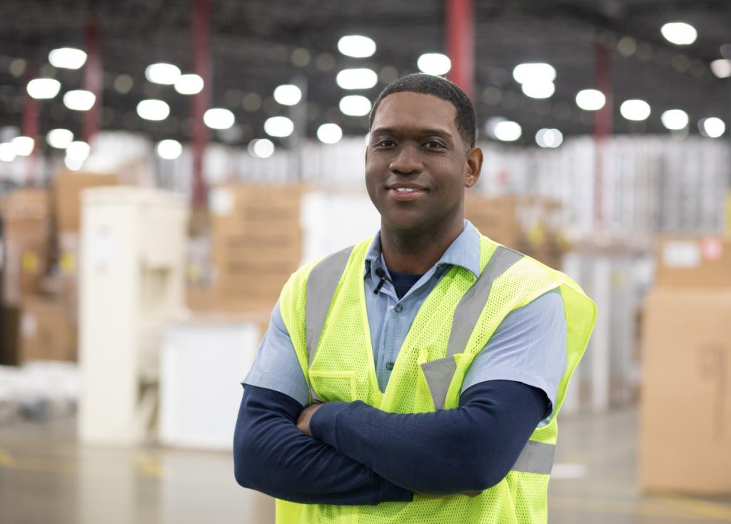 Final Mile Services driver Quincy, standing in a warehouse smiling. 