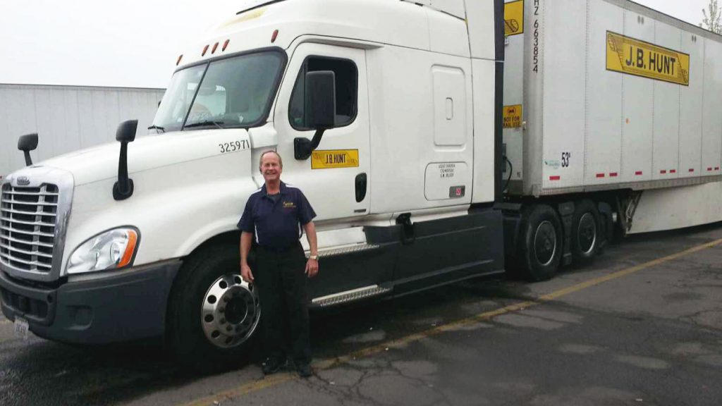 J.B. Hunt truck driver stands next to branded truck. 
