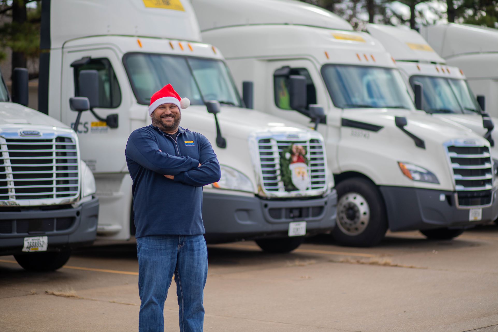 Driver Shane wears Santa hat and stands near J.B. Hunt trucks.