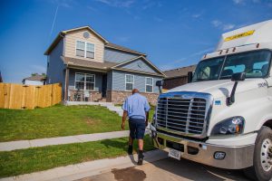 J.B. Hunt driver walks next to J.B. Hunt day cab parked in front of his house.