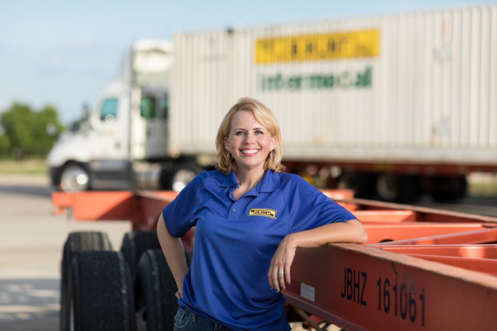 JBI driver Julia leans on equipment and smiles; J.B. Hunt Intermodal trailer is in the background.