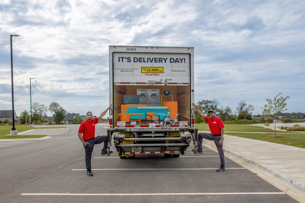 Two J.B. Hunt drivers stand behind a J.B. Hunt Final Mile Services box truck.