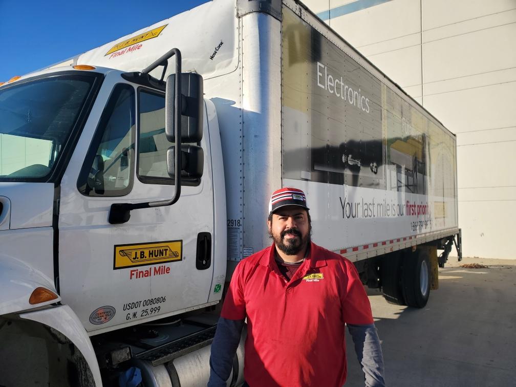 Jose stands next to his J.B. Hunt Final Mile delivery truck and smiles at the camera.