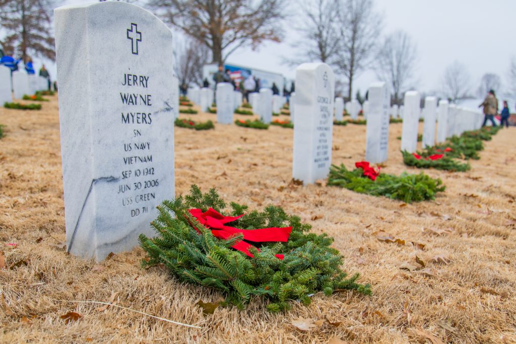 Wreaths laying on the ground in front of graves at the Fayetteville National Cemetery in Arkansas.