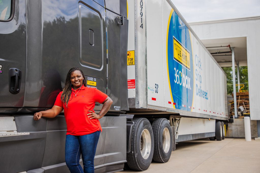 Owner operator contracted with J.B. Hunt leans on her truck and smiles.