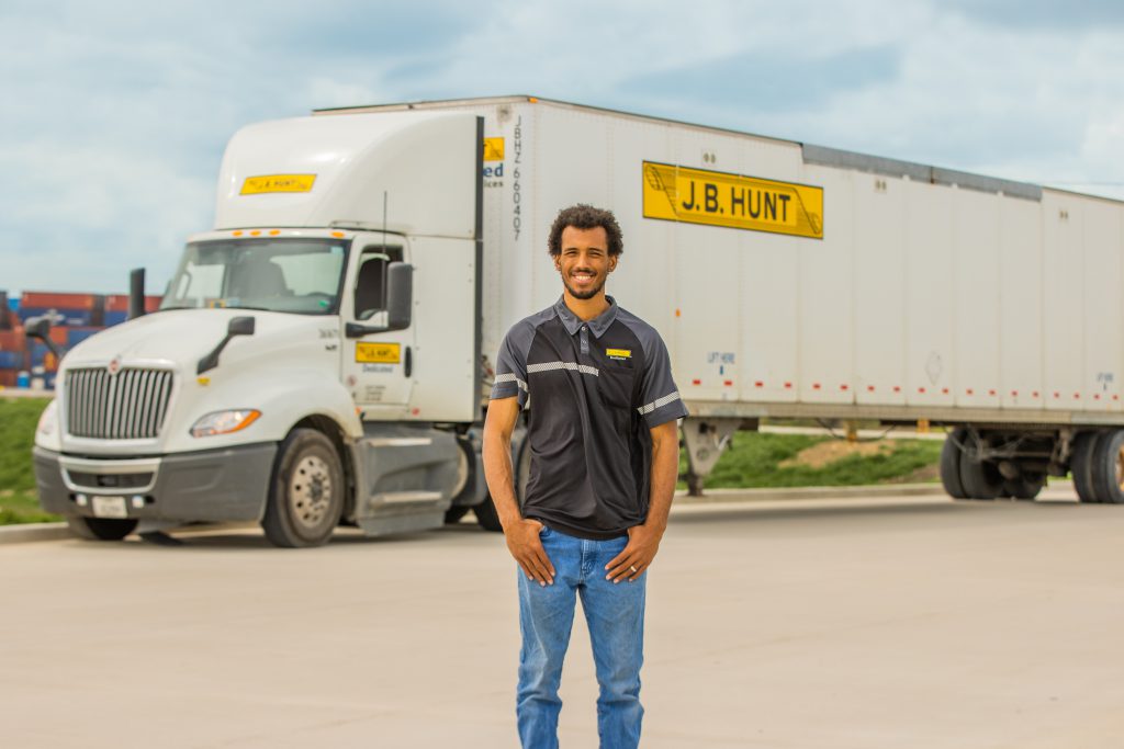 J.B. Hunt driver stands in front of a tractor and trailer.