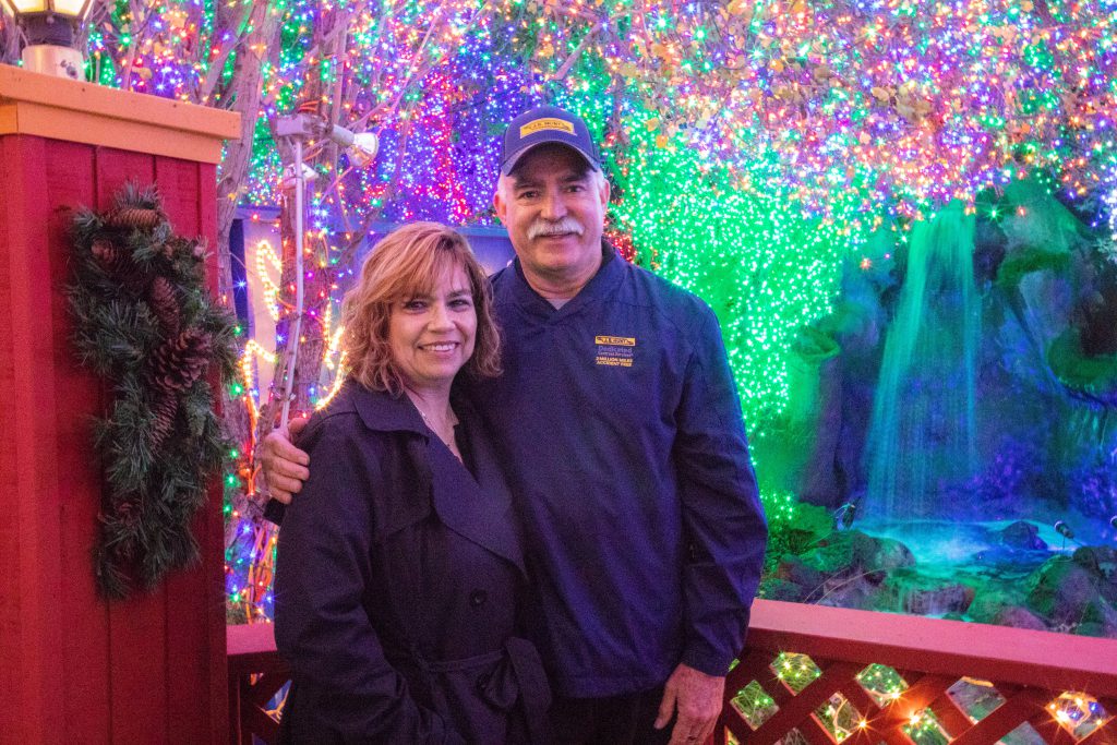 J.B. Hunt driver Juan, right, stands with his wife, left, in front of Christmas lights.
