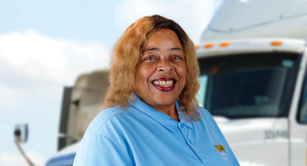 Intermodal driver Debra stands and smiles in front of a J.B. Hunt day cab.