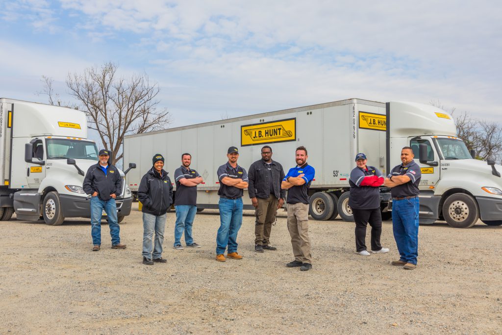 J.B. Hunt drivers stand in front of a J.B. Hunt Dedicated trailer and day cab.