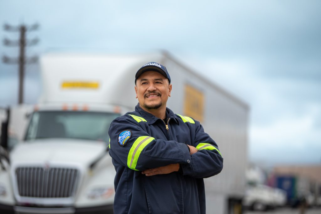 J.B. Hunt local dedicated driver Mario stands and smiles in front of a J.B. Hunt Dedicated Contract Services day cab and trailer.