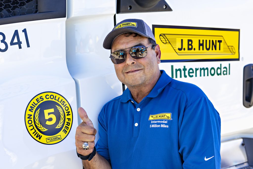 Tony, J.B. Hunt five million mile safe driver, gives a thumbs up next to his five million mile truck decal.
