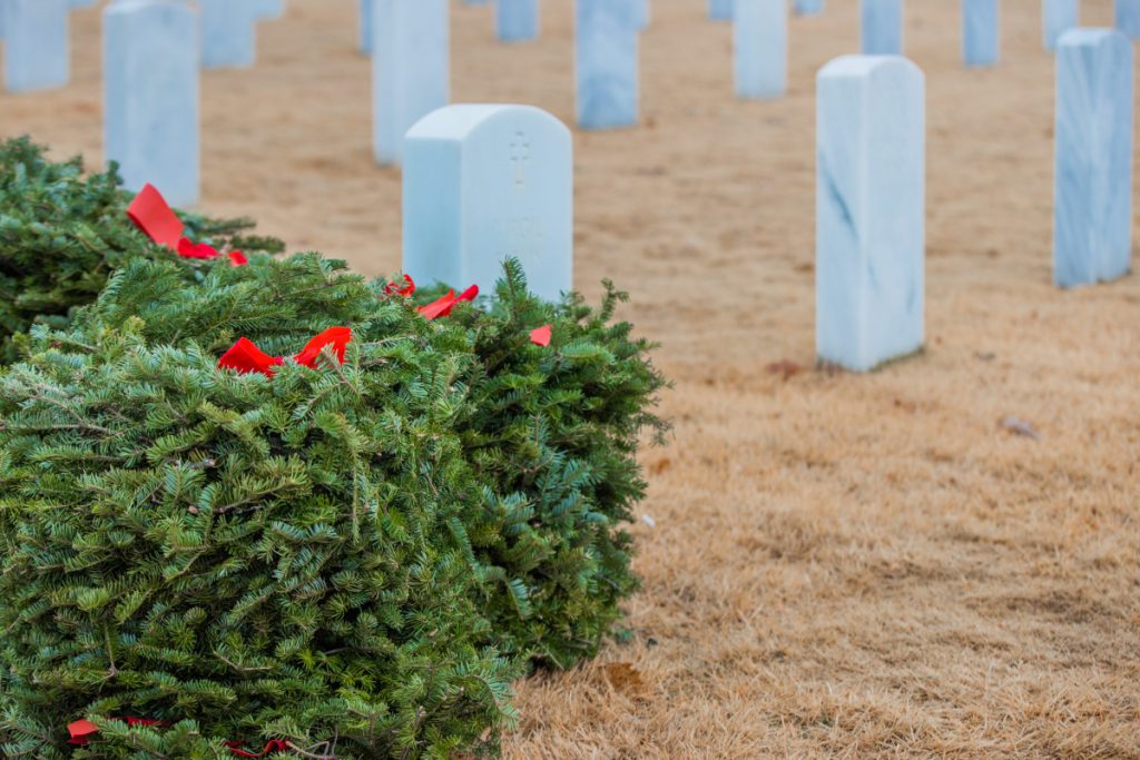 Wreaths Across America volunteers lay wreaths at a national cemetery.