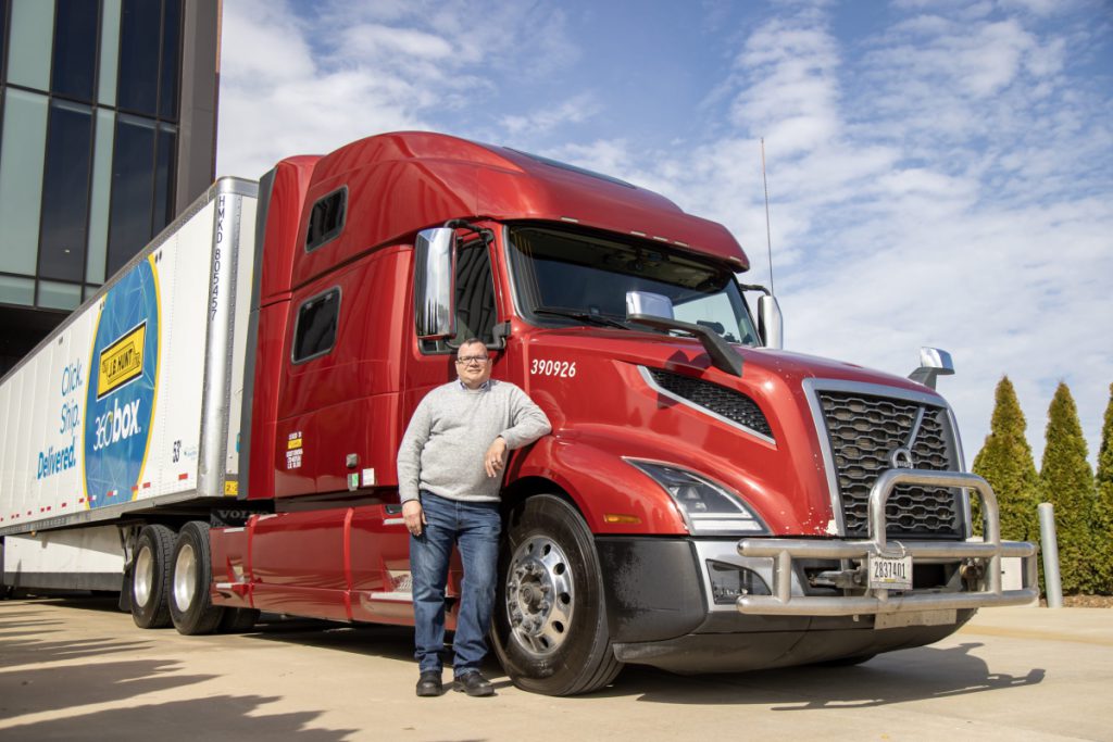 Jason, owner operator, leans on his truck and smiles.