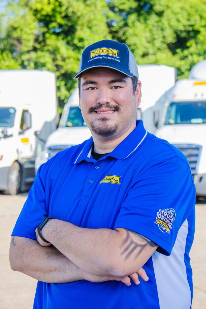 J.B. Hunt driver James stands with arms crossed and smiles.