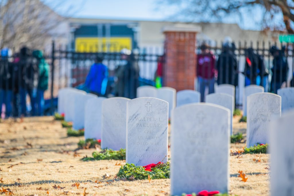 Holiday wreaths laying on graves at a national cemetery.