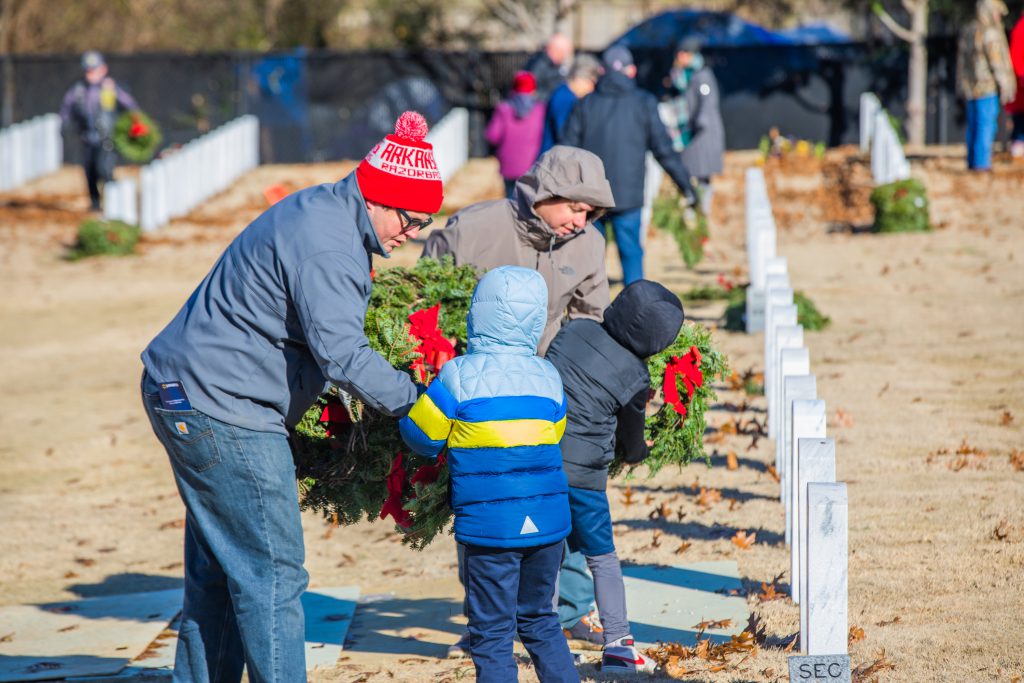 Volunteers place wreaths on graves at a national cemetery.