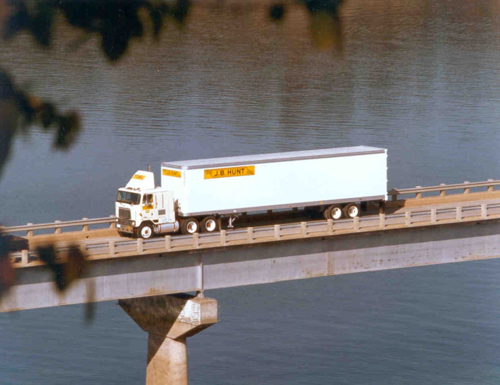 J.B. Hunt 1980s cabover truck drives over a bridge.