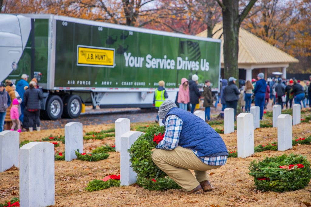 Wreaths Across America volunteer lays a wreath at a national cemetery during National Wreath Laying Day.